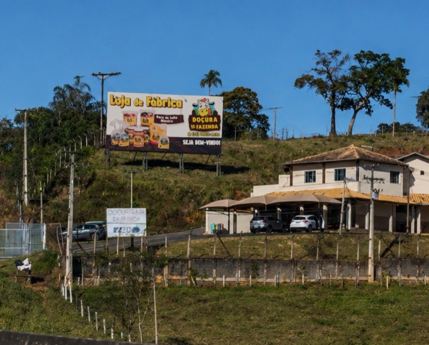 Vista externa da fábrica e do empório da Doçura da Fazenda com outdoor às margens da rodovia