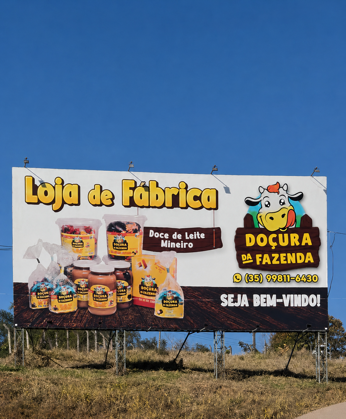 Outdoor da Loja de Fábrica Doçura da Fazenda com produtos e mensagem de boas-vindas